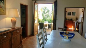 A dining area with a table set for two, a wooden cabinet, and a view of the outdoor patio.