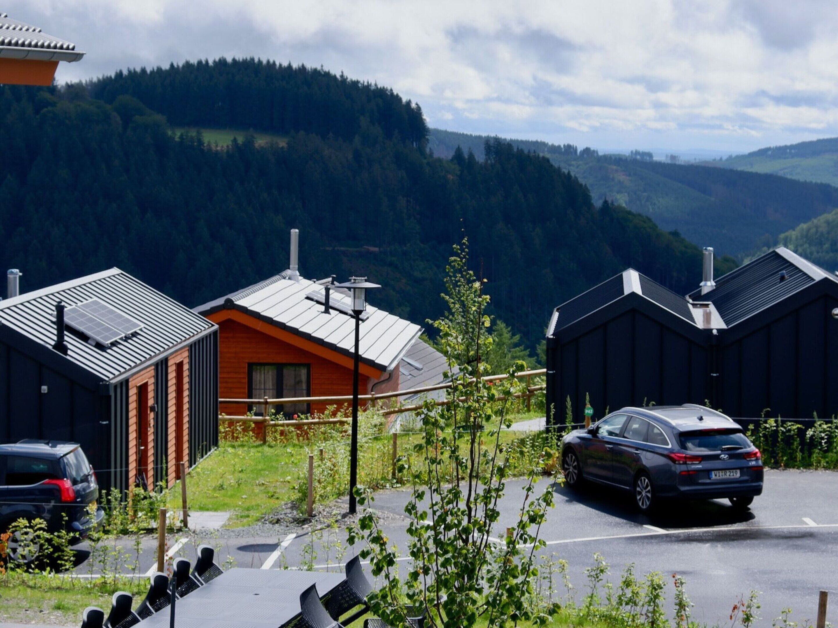 A modern building with a sloped roof, a solar panel, and a car parked in front.