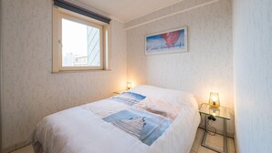 Quarto com cama, janela, pintura e mesa de cabeceira com abajur.