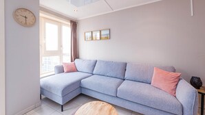 Uma sala de estar moderna com um sofá seccional, uma mesa de centro de madeira redonda e um relógio de parede.