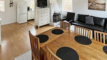 A modern living room with a wooden dining table, black chairs, a black sofa, and a fireplace.