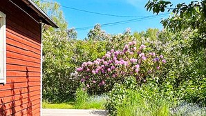 Un edificio de madera rojo con un sendero que lleva a un jard ín de flores rosas.