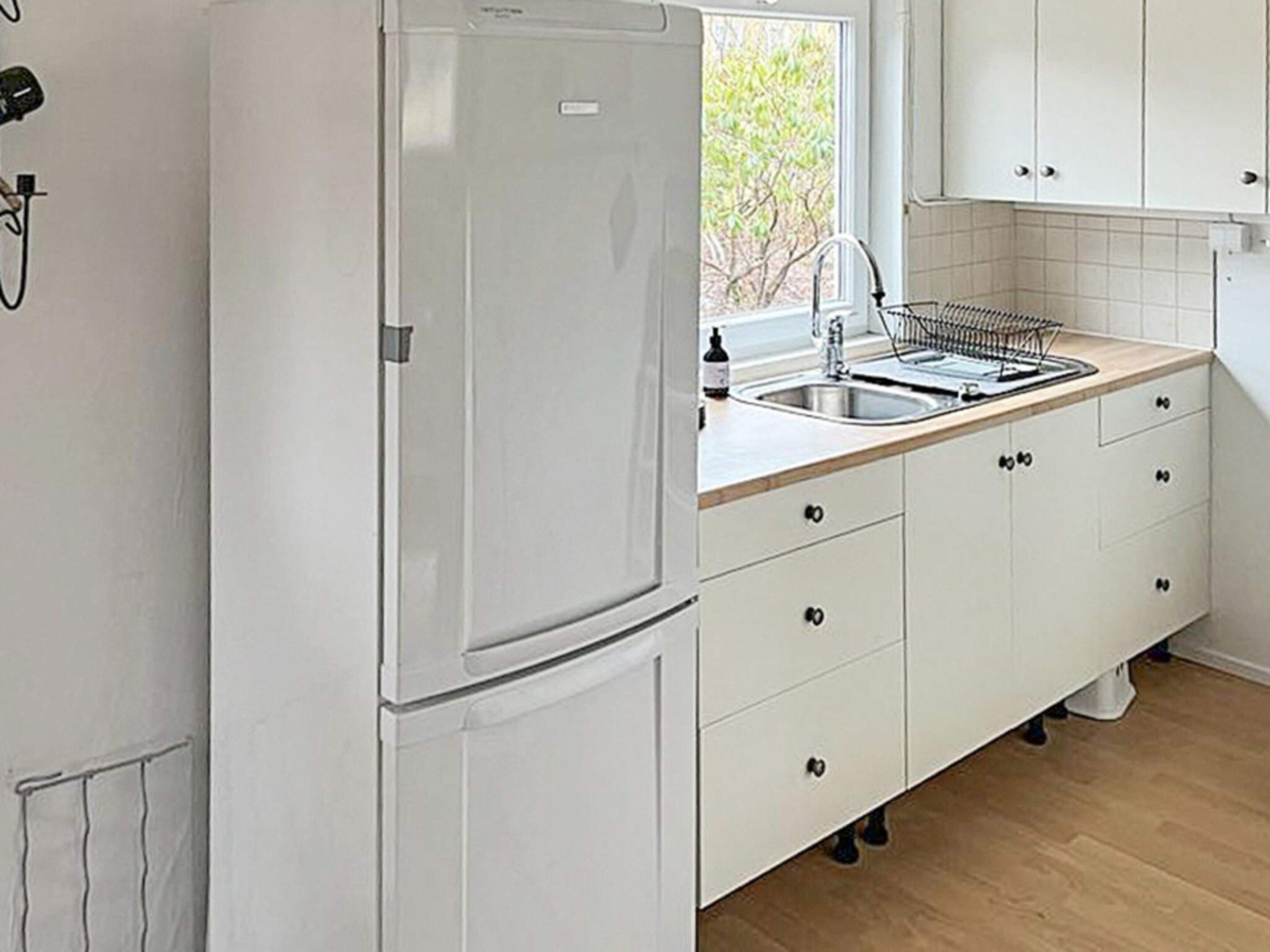 A kitchen with a white refrigerator, a sink, and cabinets.