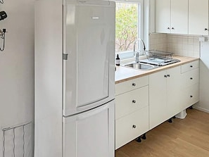 A kitchen with a white refrigerator, a sink with a faucet, and cabinets with drawers. - 4 Person Holiday Home in Sodertalje (Sodertalje)