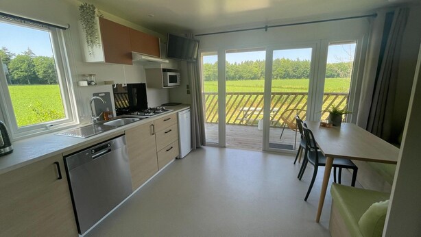 Una cocina moderna con comedor, ventanas amplias y vistas a un campo verde.