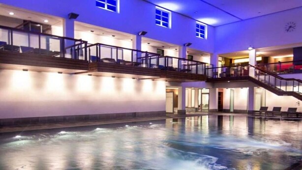 A large indoor swimming pool with a hot tub, multiple levels with balconies, and a modern architectural design. - Lively Apartment in Norderney (Norderney)