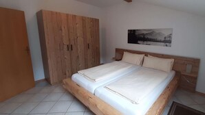 A bedroom with a wooden bed, a large wardrobe, and a mountain landscape painting on the wall. - Ferienwohnung in Bayrischzell (Bayrischzell)