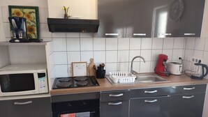 A compact kitchen with a microwave, stove, oven, sink, and various appliances. - Cottage alsace bossue (Weyer)