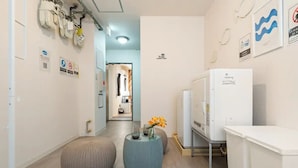 A hotel corridor with a kitchenette, a refrigerator, and a small table with a vase of flowers. - Wagyu House (Osaka)