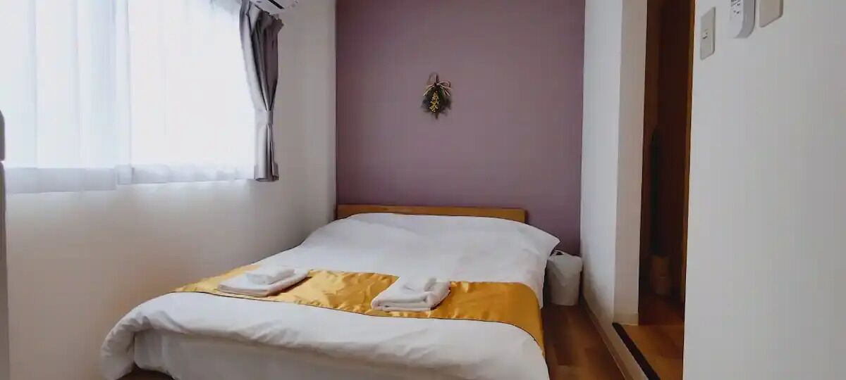 A neatly made bed with white and yellow bedding, a wooden headboard, and a wall-mounted decoration.