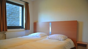 A double bed with white bedding, a wooden headboard, and a window with curtains. - House in Belgium With Pool Near Les Jardins du Golf (Durbuy)