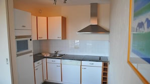 A compact kitchen with white cabinets, a microwave, a sink, and a stainless steel range hood. - House in Belgium With Pool Near Les Jardins du Golf (Durbuy)