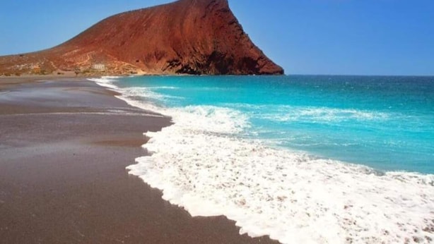 A beach with a large, reddish-brown hill in the background and turquoise waters. - Apartment Tenerife Near Sea & Pool (Santiago del Teide)
