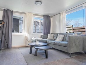 A modern living room with a grey sofa, two round coffee tables, and a lamp. - Modern Chalet on the Wadden Sea, Near the Beach (Westerland)