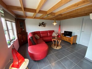 Un salon avec un canapé rouge, une table basse en bois, un téléviseur et une cheminée.