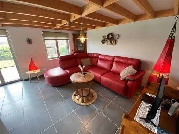 Un salon avec un canapé en cuir rouge, une table basse ronde en bois et une lampe rouge.