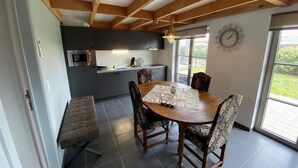 Una cocina moderna con armarios oscuros, una mesa de comedor de madera y sillas estampadas, además de un banco.