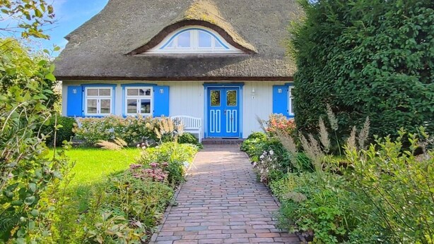 A traditional house with a thatched roof, a blue door, and a brick pathway leading to the entrance. - Captain House South Cats 8 (Wieck auf dem Darss)
