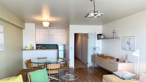 Eine moderne Wohnung mit Essbereich, Küchenzeile und Wohnraum mit Sofa und Lampe.