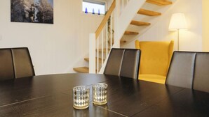 A dining area with a dark wooden table, two clear glass candle holders, and a yellow chair.