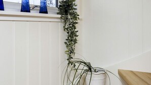 A window sill with three blue glass bottles and a potted plant.