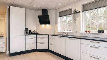 Una cocina moderna con gabinetes blancos, encimera negra y estufa integrada.