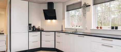 A modern kitchen with white cabinets, a black countertop, and a built-in stove.