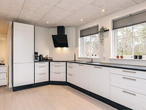 A modern kitchen with white cabinets, a black countertop, and a built-in stove. - 6 Person Holiday Home in Laeso-by Traum (Læsø)