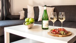 A dining table with a bottle of wine, two glasses of wine, a bowl of green apples, and a plate of food. - The Moselle Gate to Koblenz (Lehmen)
