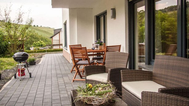 An outdoor patio with a table and chairs, a grill, and wicker furniture. - The Moselle Gate to Koblenz (Lehmen)