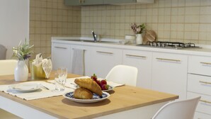 A kitchen with a wooden table set for breakfast, including croissants and strawberries. - Belvilla by OYO Comfortable Apartment With Pool (Garda)