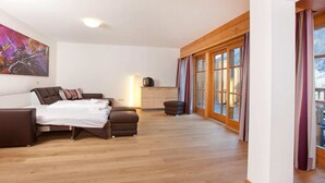 A bedroom with a bed, bedside table, lamp, and a large window with curtains. - Chalet in Pinzgau Near Ski Slopes (Wald im Pinzgau)