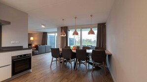 Una cocina moderna con zona de comedor, suelo de madera e iluminación colgante.