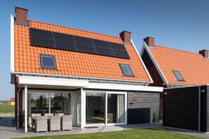 A modern house with a sloped roof, solar panels, a covered patio, and a garage. - Holiday Home in Colijnsplaat With Sauna (Colijnsplaat)