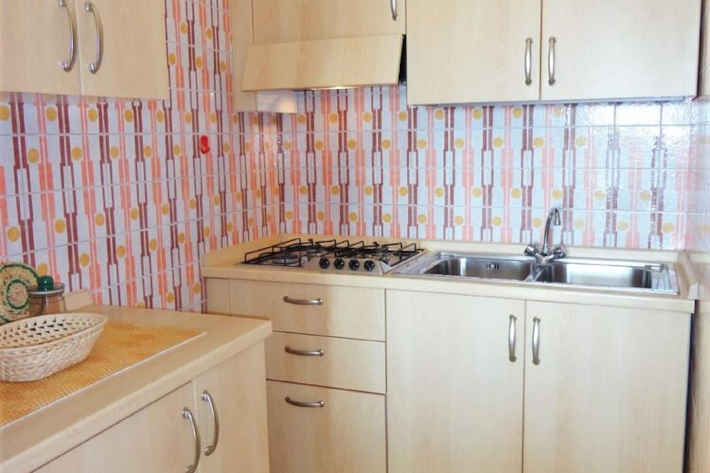 A kitchen with a gas stove, sink, and wooden cabinets.