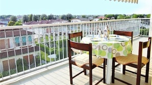 Een balkon met een tafel en stoelen, met uitzicht op een woongebied met huizen en groen.