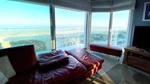 Een moderne slaapkamer met een groot bed, een televisie en uitzicht op de kustlijn.