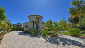 A building with a circular tower, surrounded by a stone pathway and various plants. - Esperanza - Javea, Costa Blanca (Javea)