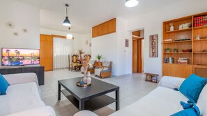 A living room with a sofa, coffee table, TV, and wooden shelves. - Mike s House in Kremasti Near the Beach Rhodes (Rhodes)