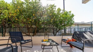 An outdoor seating area with metal chairs and a table, surrounded by a metal fence and trees with fruit. - Mike s House in Kremasti Near the Beach Rhodes (Rhodes)