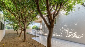 A courtyard with trees, a tiled floor, and a building with a balcony. - Mike s House in Kremasti Near the Beach Rhodes (Rhodes)