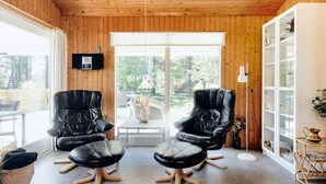 A modern interior with two black leather chairs, a white cabinet, and a large window with a view of greenery. - 6 Person Holiday Home in Strandby (Strandby)