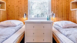 A cozy room with two single beds, a white dresser, a window with a view of snow-covered trees, and wall-mounted lamps. - 6 Person Holiday Home in Strandby (Strandby)