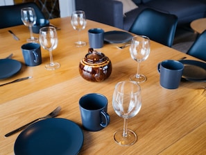 A dining table set with plates, cutlery, and glasses, with a teapot in the center.