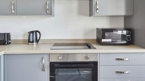 Cucina con mobili grigi, un forno a microonde, un tostapane e un bollitore.
