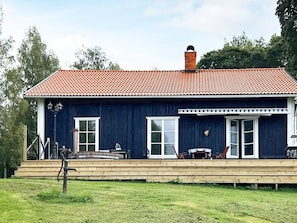 A two-story house with a red-tiled roof, a wooden deck, and a chimney. - 4 Star Holiday Home in Tronodal (Trönödal)