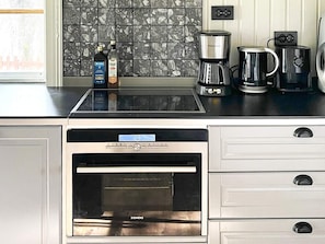 A kitchen with a built-in oven, a coffee maker, and a bottle of liquor on the counter. - 4 Star Holiday Home in Tronodal (Trönödal)