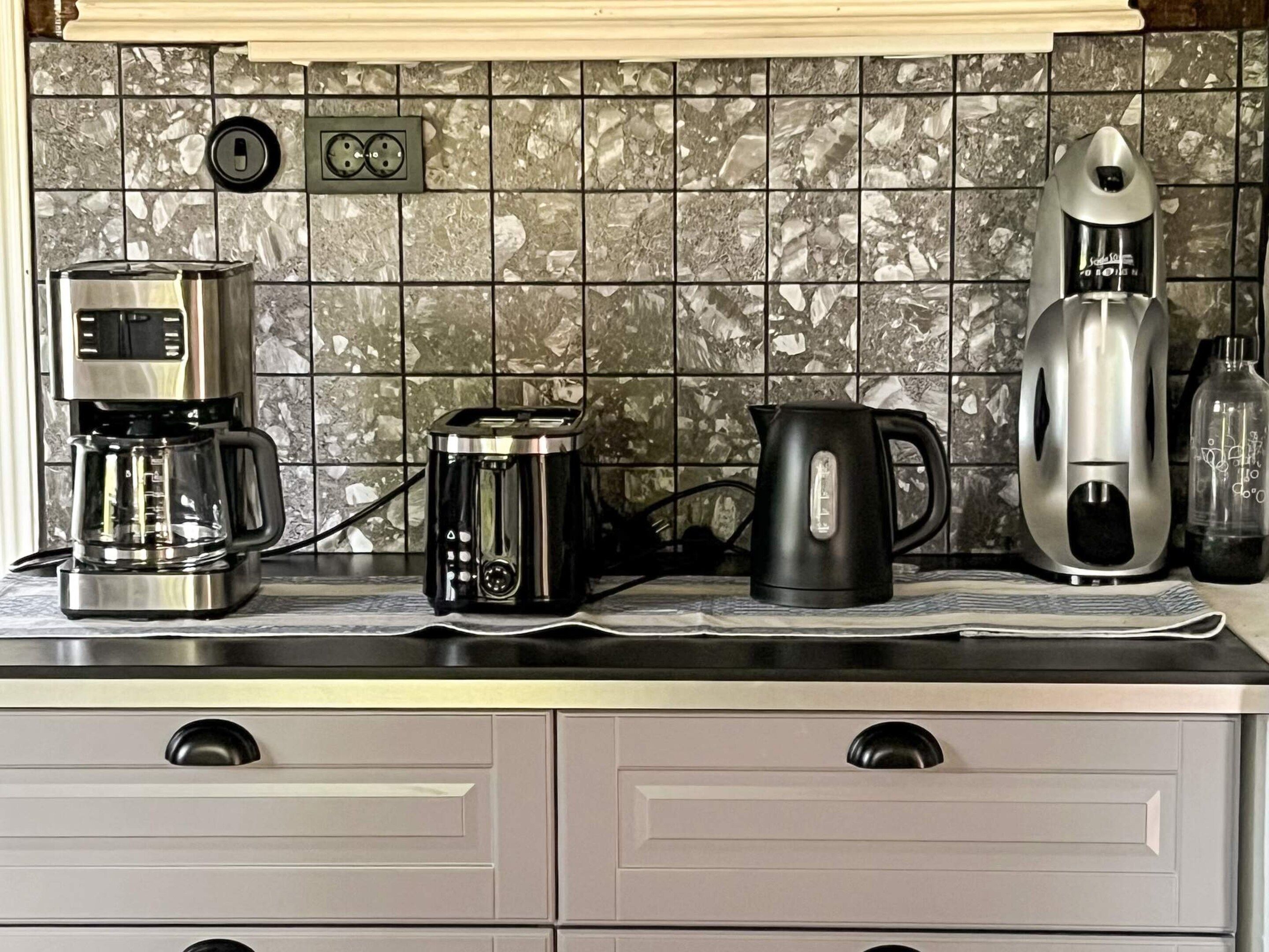 Una encimera de cocina con cafetera, tostadora, hervidor y tetera eléctrica.