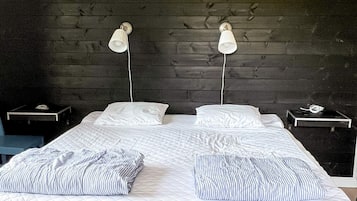 Una cama con dos almohadas, una mesita de noche y una lámpara a cada lado.