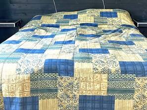 A bed with a quilted bedspread featuring geometric and floral patterns. - 4 Star Holiday Home in Tronodal (Trönödal)